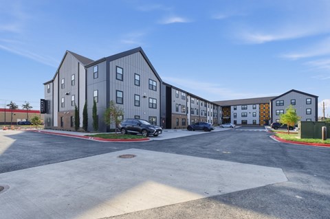 A parking lot in front of a grey building.