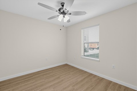 A room with a ceiling fan and a window with blinds.