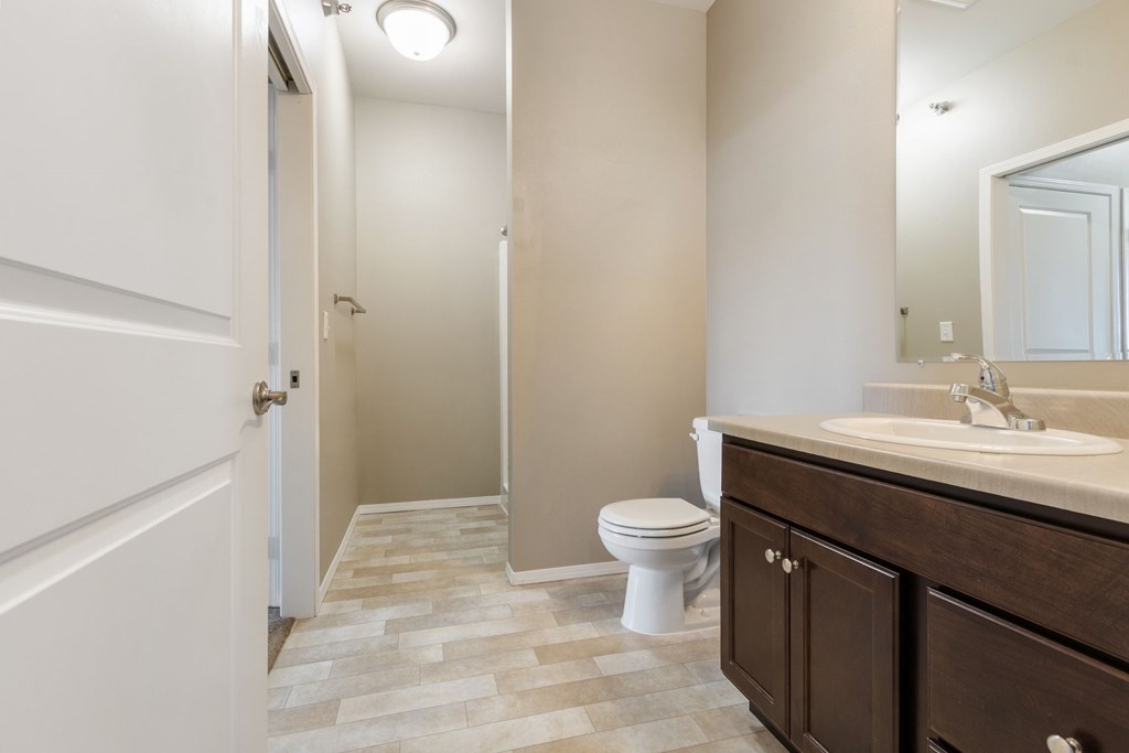 A bathroom with a toilet, sink, and mirror.