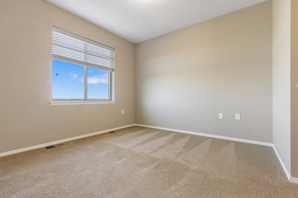 A room with a carpeted floor and a window with blinds.