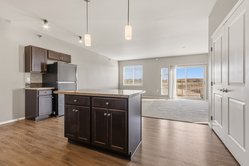 A kitchen with dark brown cabinets and a black refrigerator.