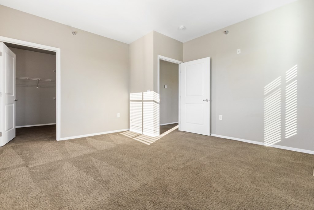 A room with a carpeted floor and two open doors.