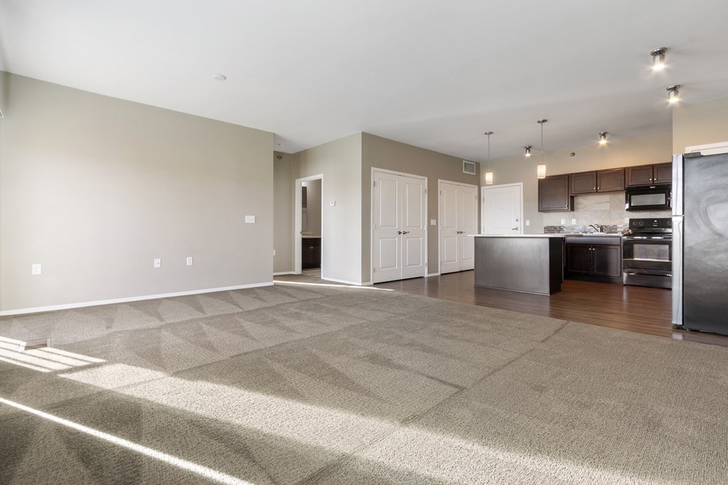 A spacious room with a kitchen area in the background.