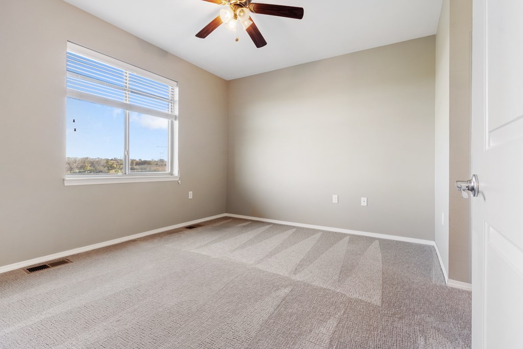 A room with a ceiling fan and a carpeted floor.