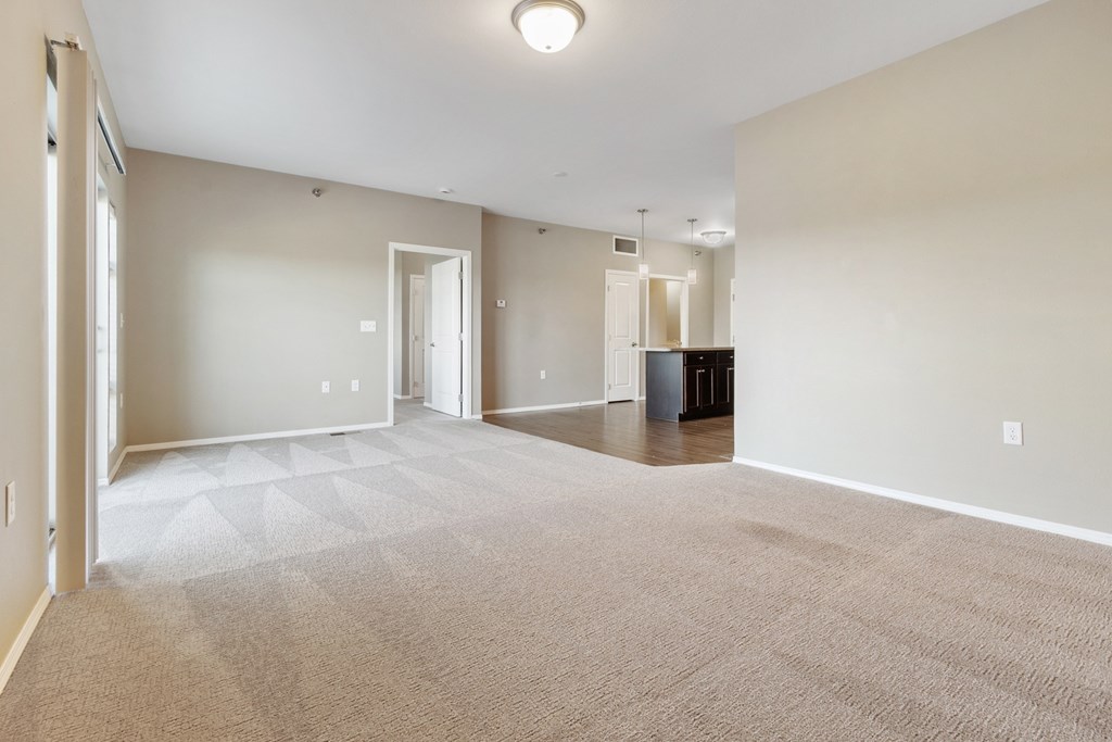A large, empty room with a carpeted floor and white walls.