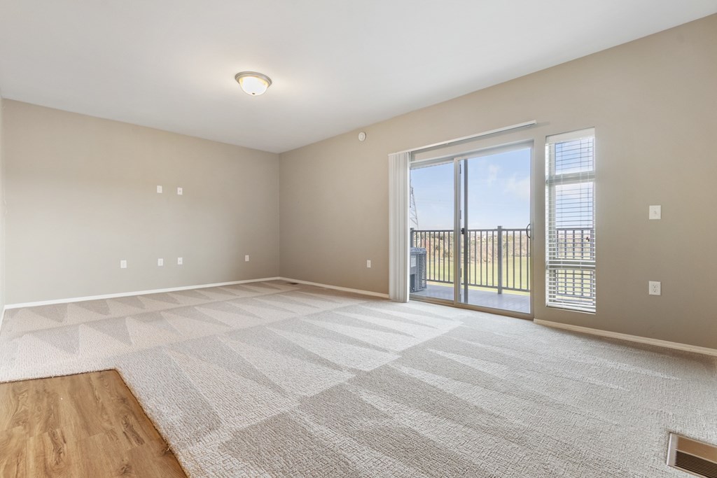 A spacious room with a large rug and sliding glass doors.