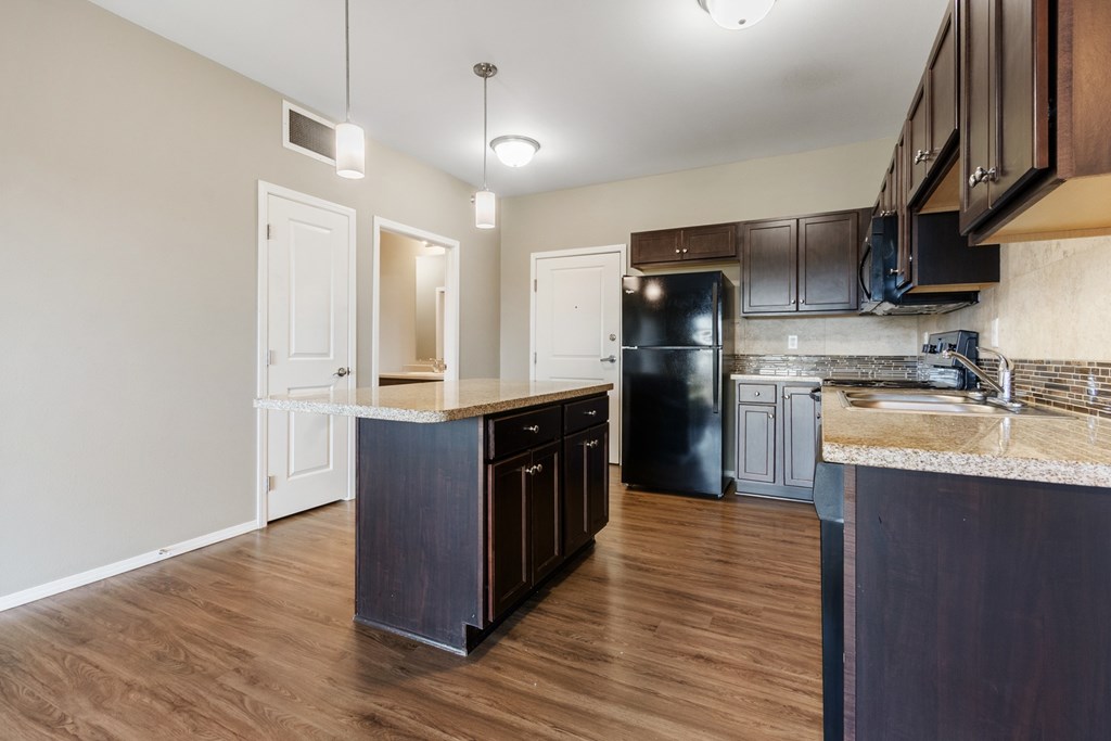 A kitchen with dark wood cabinets and a black refrigerator.