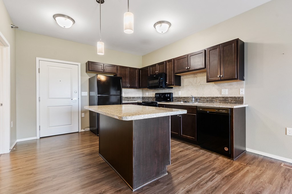 A kitchen with dark brown cabinets and black appliances.