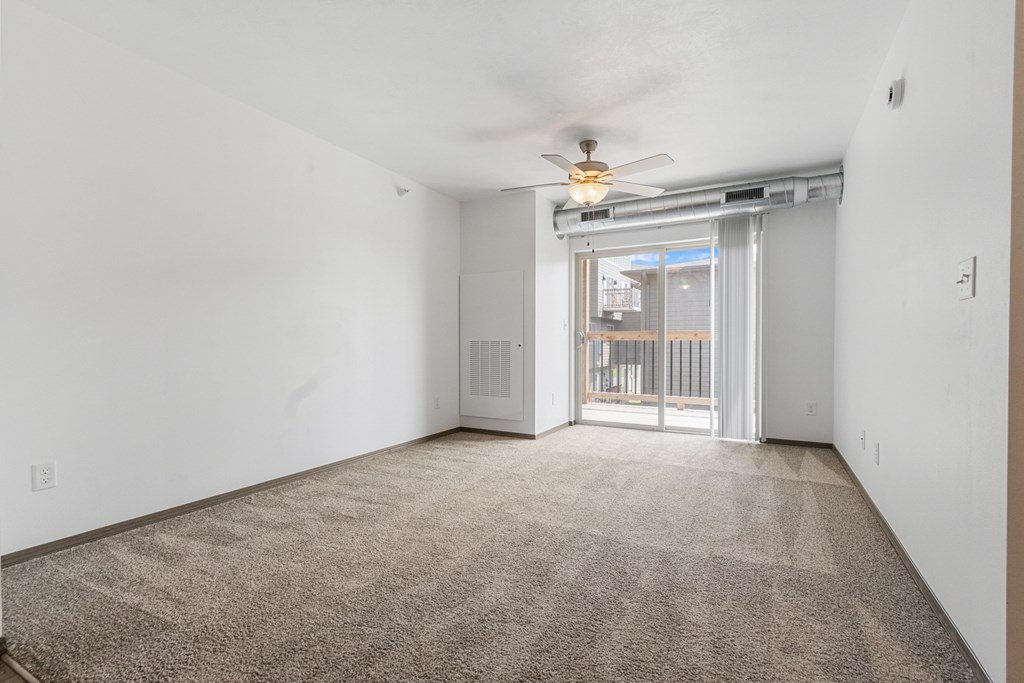 A room with a carpet floor and a ceiling fan.