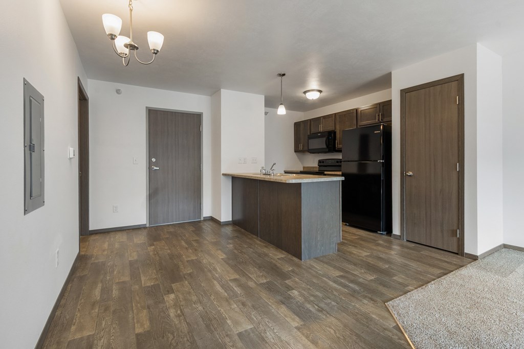 A kitchen area with a wooden floor and a bar area.