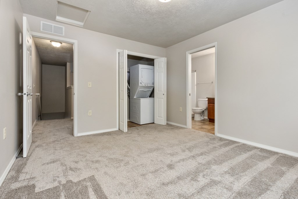 A room with a carpeted floor and a white refrigerator.