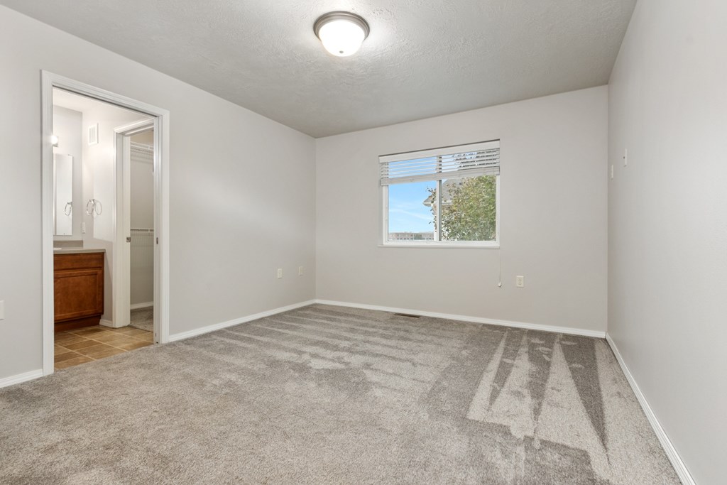 A spacious room with a carpeted floor and a window.