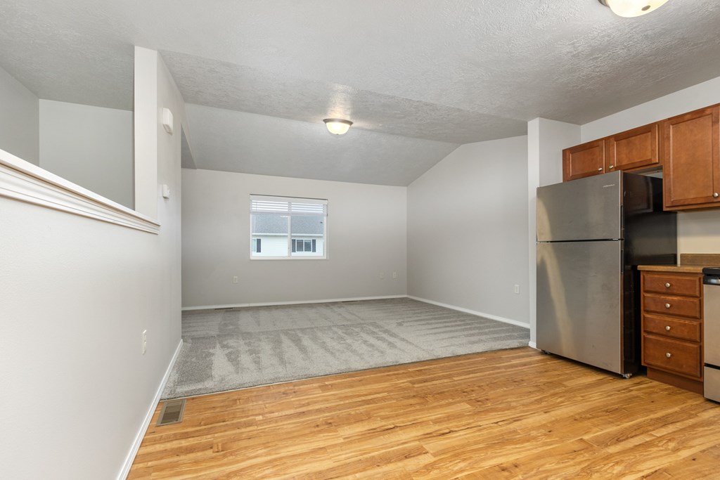 A kitchen area with a refrigerator, microwave, and wooden cabinets.
