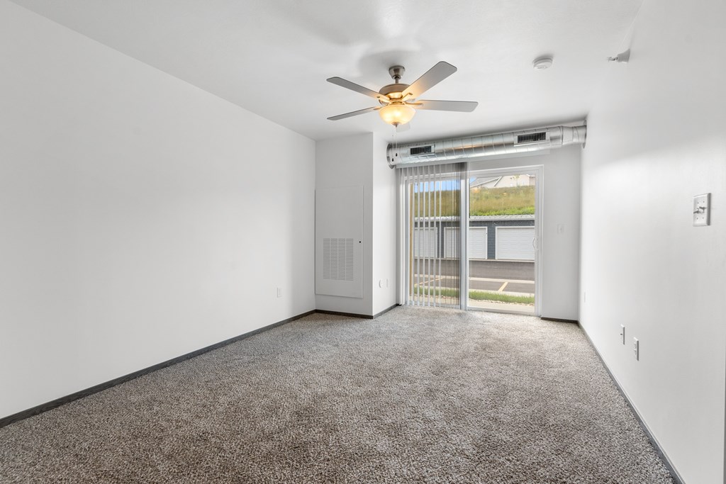 A room with a ceiling fan and carpeted floor.