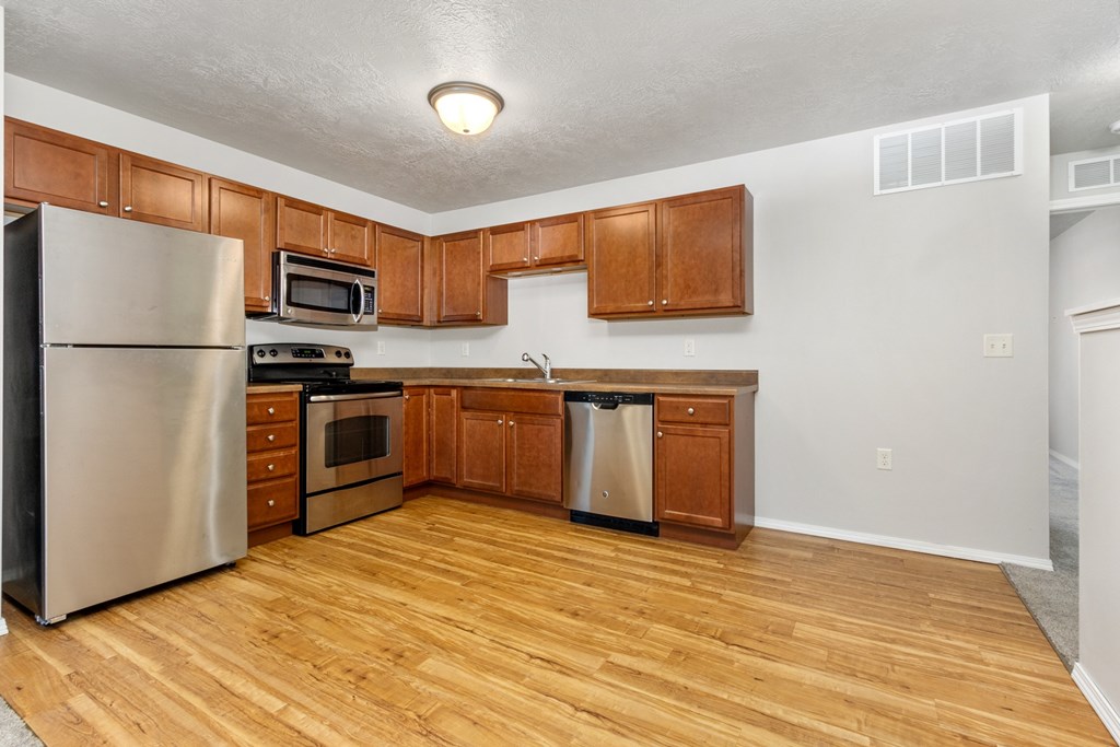 A kitchen with wooden cabinets and a stainless steel refrigerator.