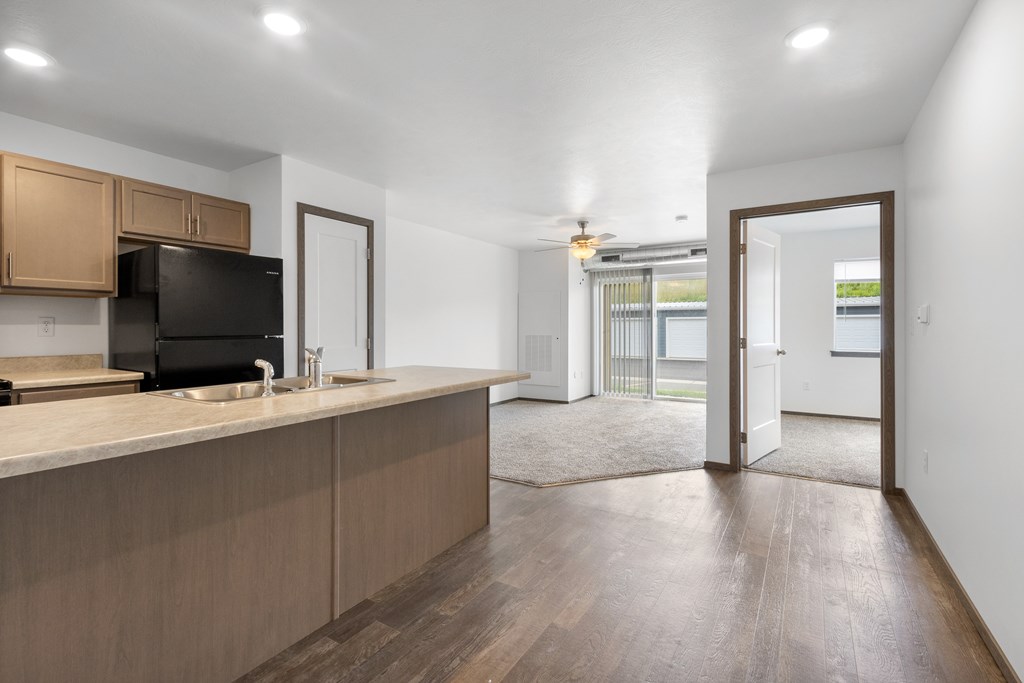 A kitchen with wooden cabinets and a black fridge.