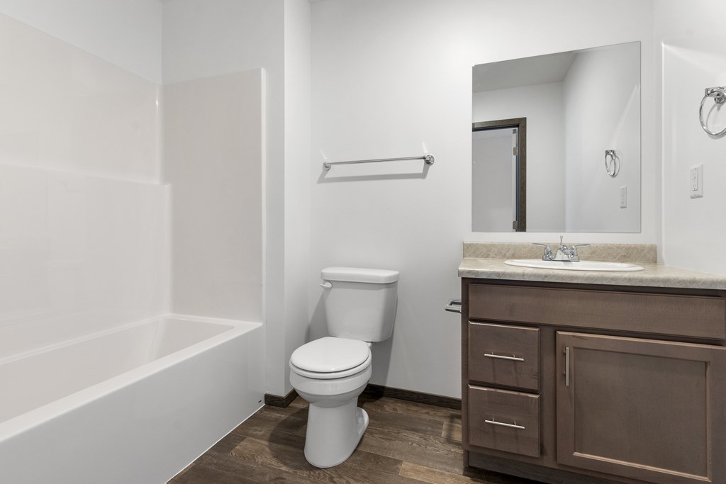 A white toilet sits in a bathroom with a brown cabinet.