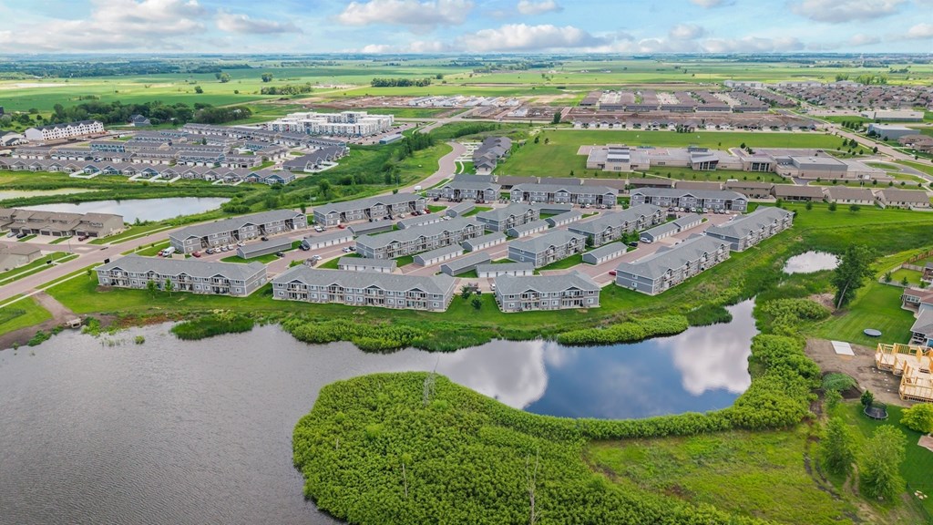 A bird's eye view of a residential area with houses surrounded by water and greenery.