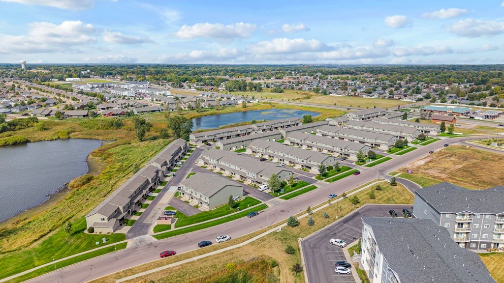 A large apartment complex sits next to a body of water with a road running through it.
