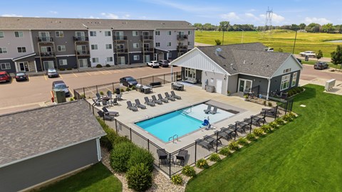 A large apartment complex with a pool and a small house.