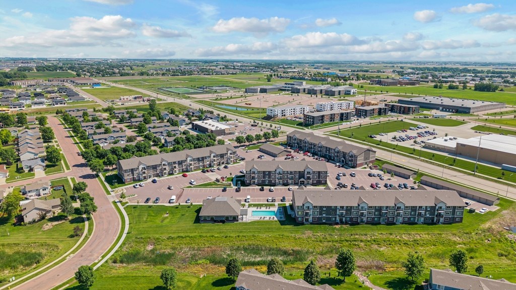 A large, modern building complex with a parking lot in front.
