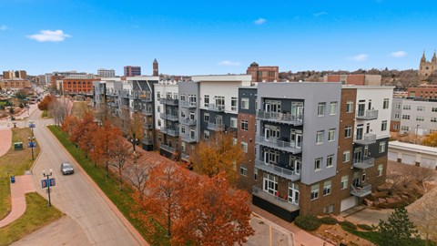 A street view of a residential area with apartment buildings and trees.