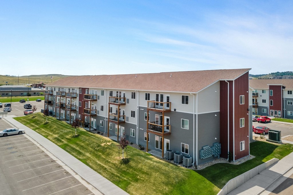 an aerial view of an apartment building with a parking lot and grass