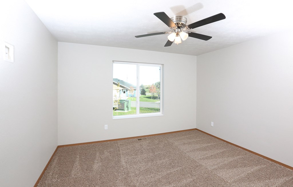 an empty room with a ceiling fan and a window
