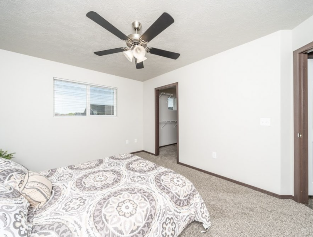 a bedroom with a bed and a ceiling fan