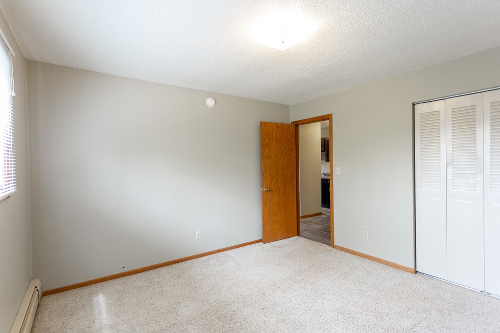 an empty living room with a door to a bedroom