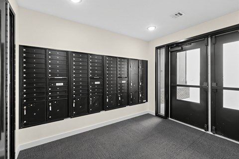 A room with a row of black lockers on the wall.