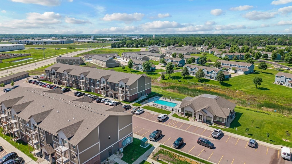 A large apartment complex with a swimming pool and a parking lot.