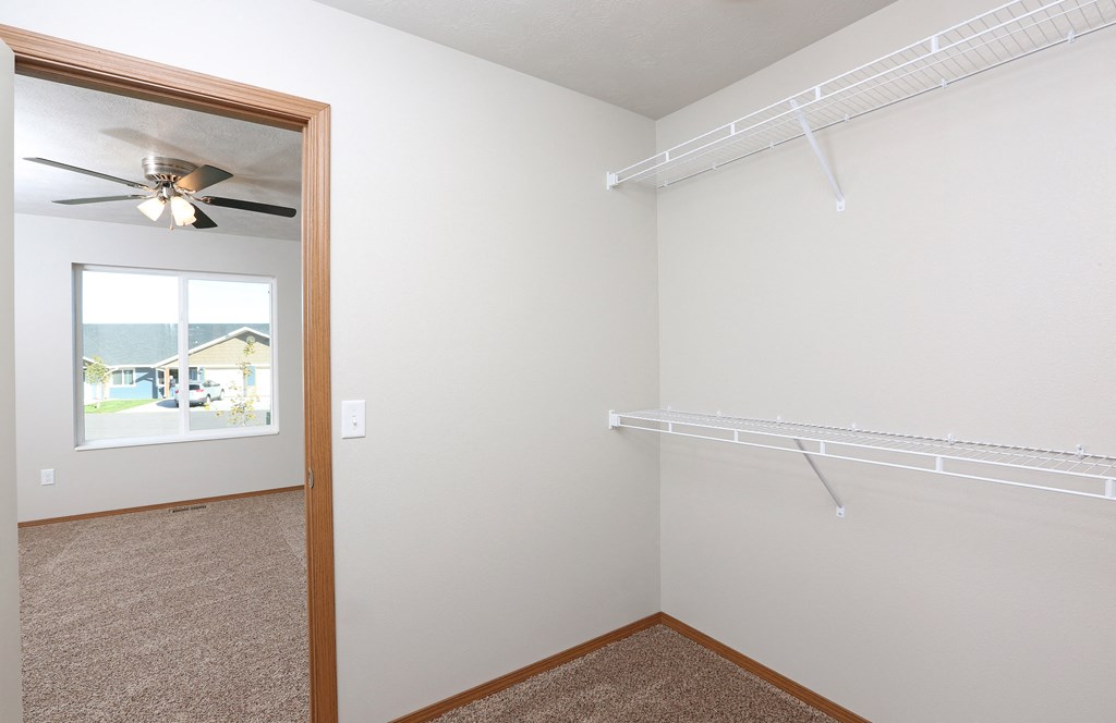 an empty closet with a ceiling fan and a window