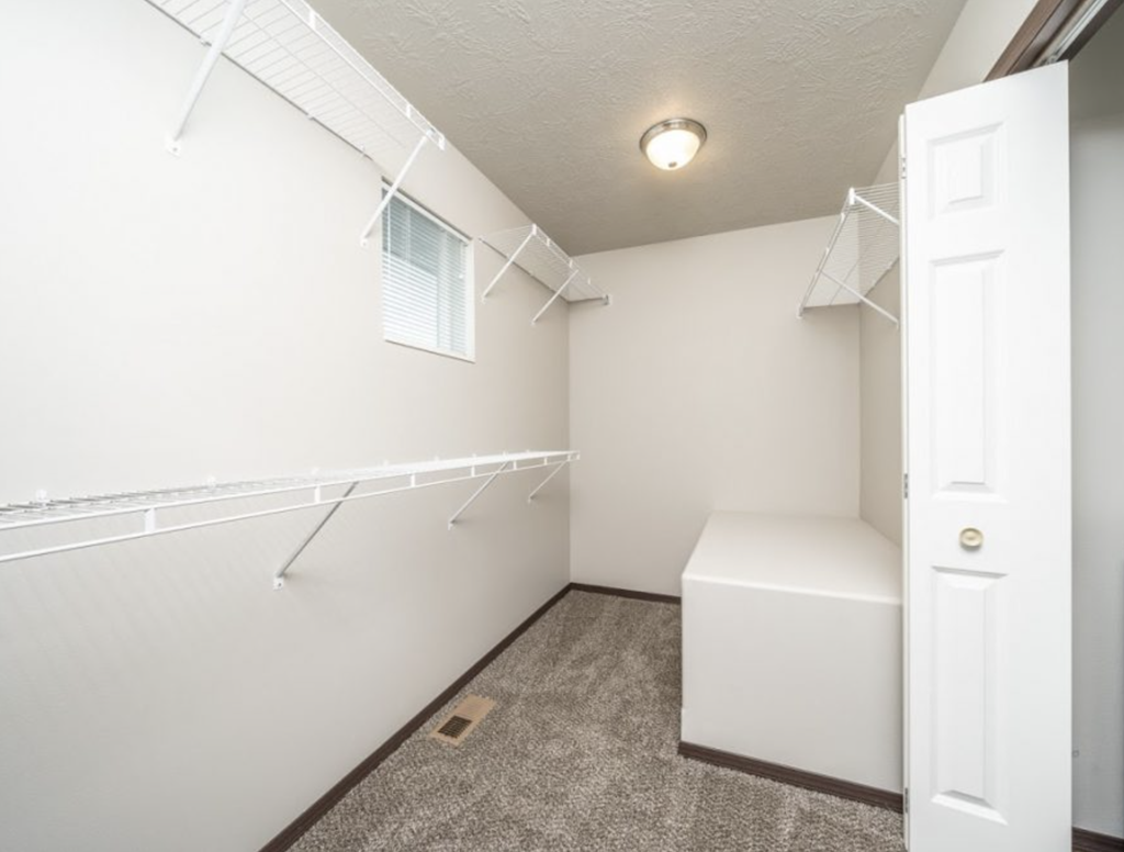 the closet in the master bedroom of a home with white walls and a white door