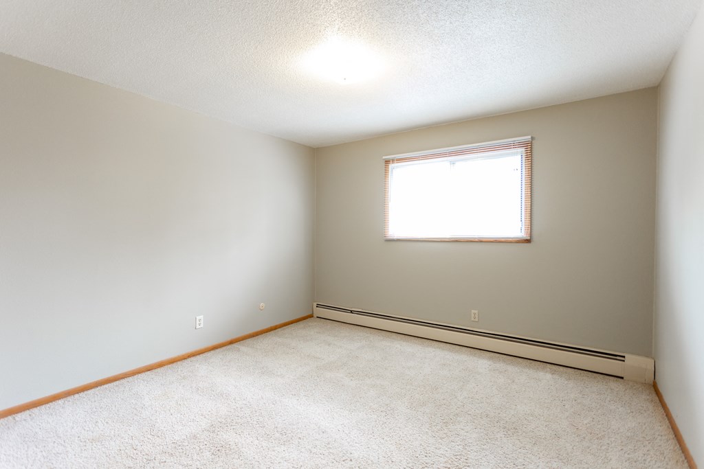 an empty room with a window and a carpet