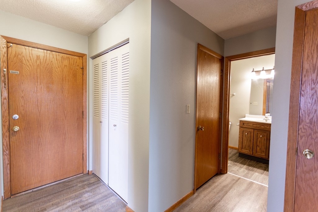 an empty hallway with a door to a bathroom and a closet
