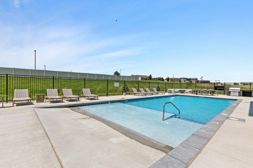 a swimming pool with chairs and a fence around it