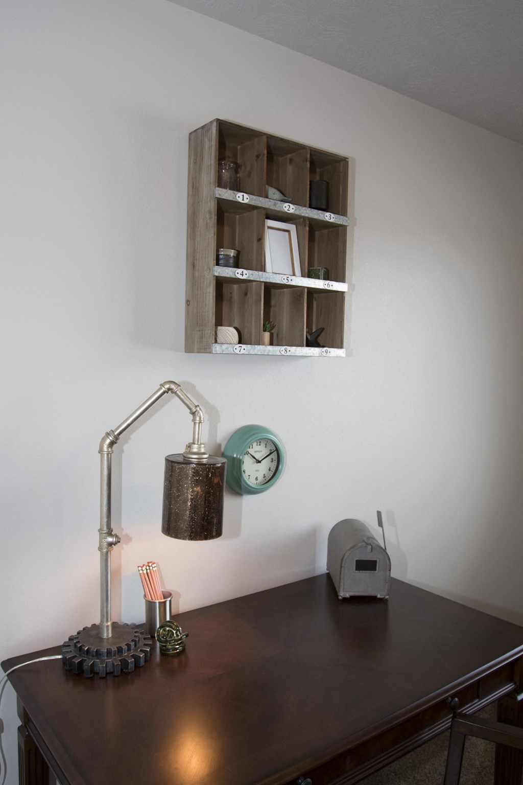 a desk with a lamp and a clock and a shelf on the wall