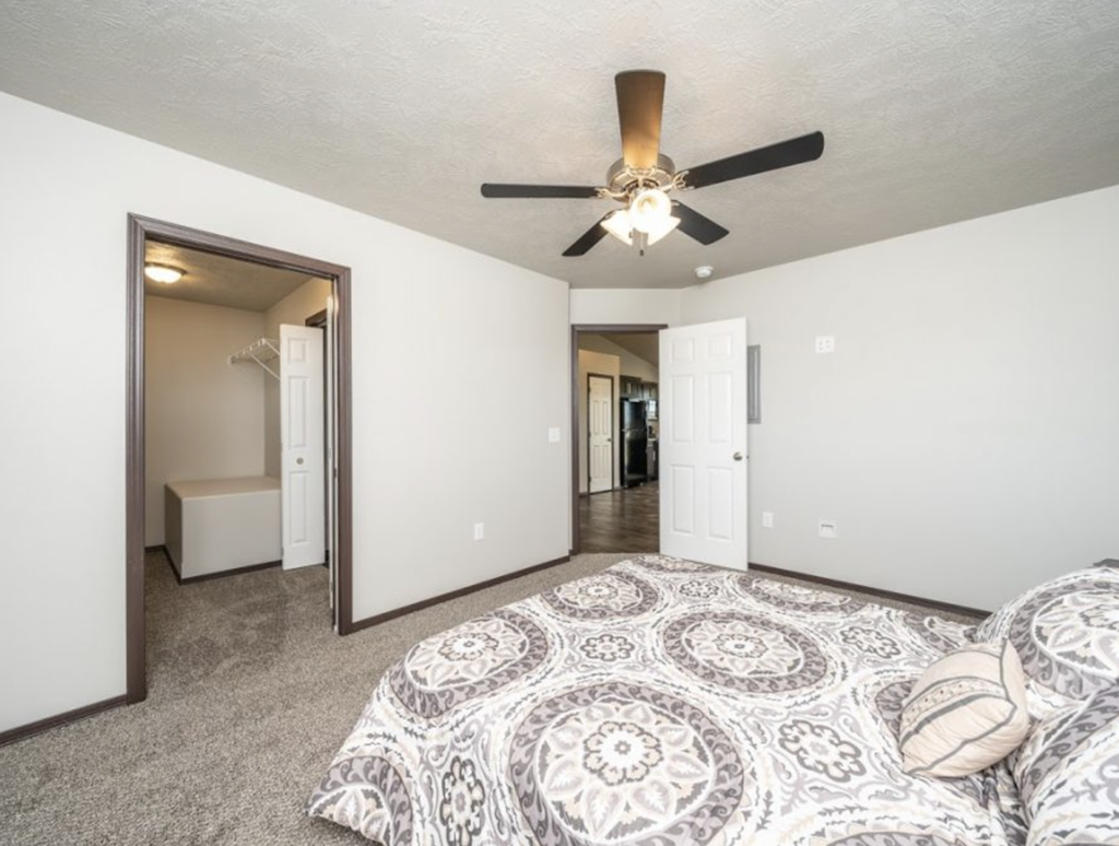 a bedroom with a ceiling fan and a bed