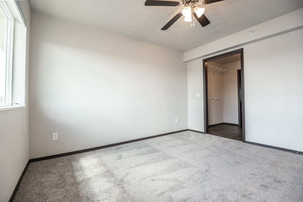 an empty living room with white walls and a ceiling fan
