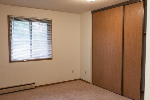 an empty room with a window and a closet