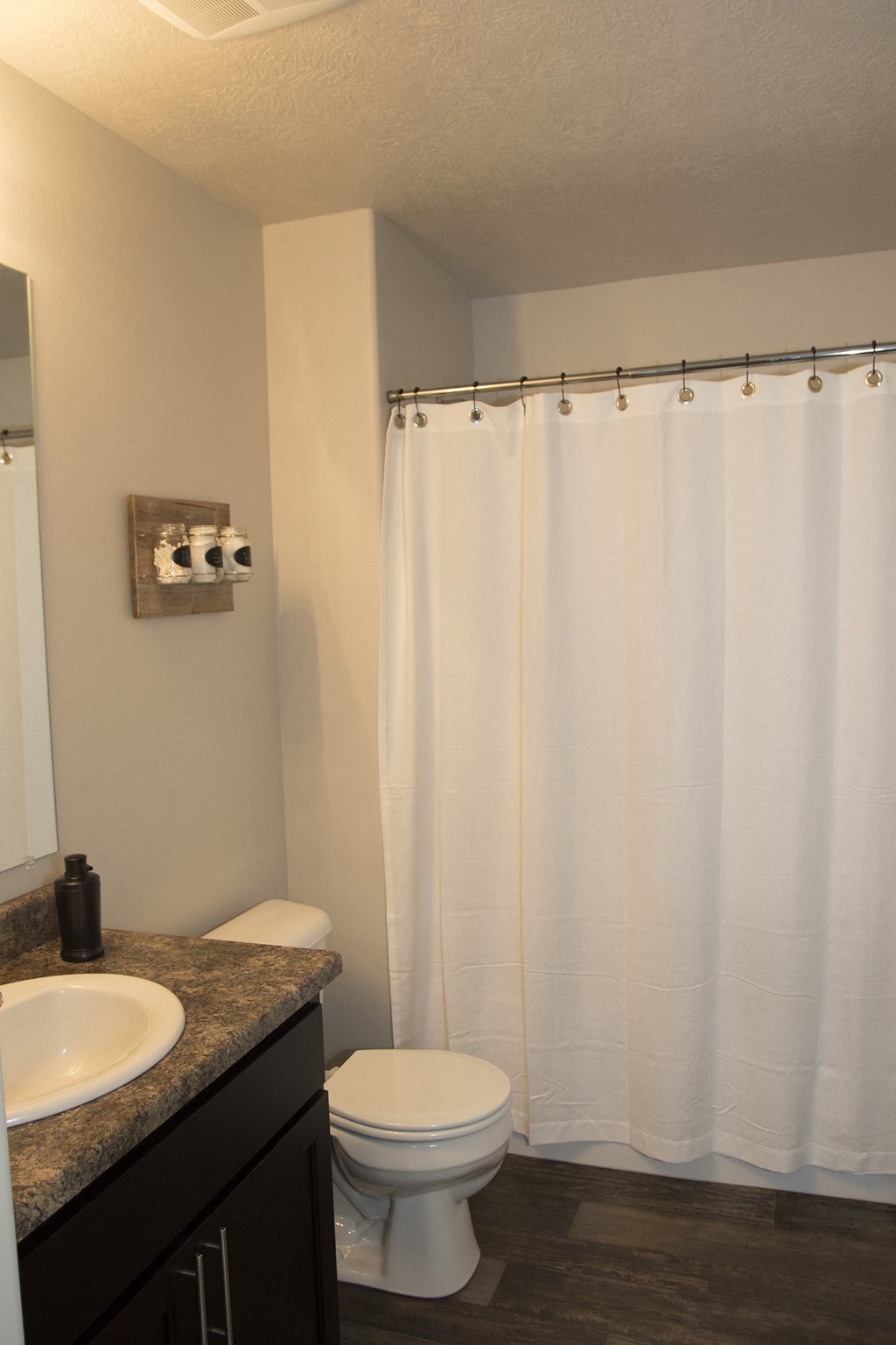 a bathroom with a white shower curtain and a toilet and sink