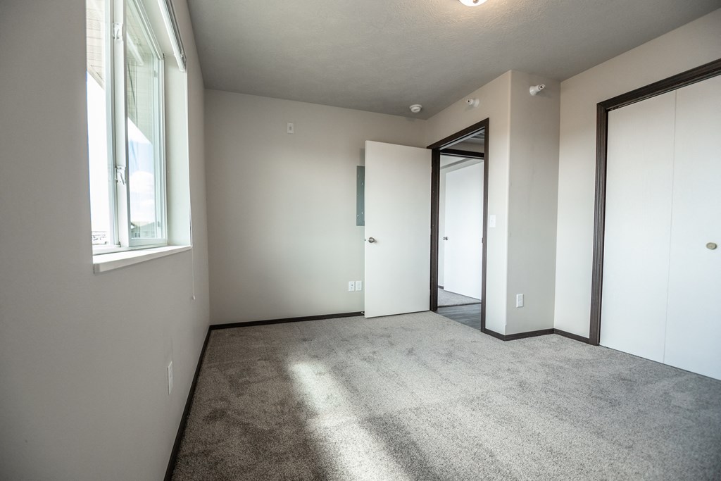an empty living room with a door to a closet and a window