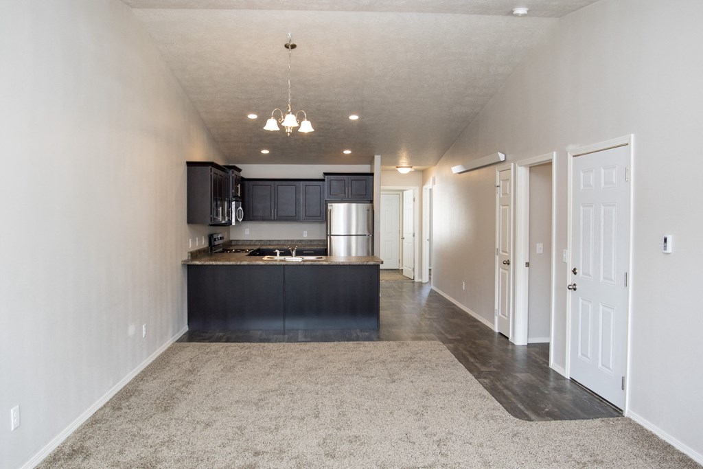 an empty kitchen and living room with black cabinets and white walls
