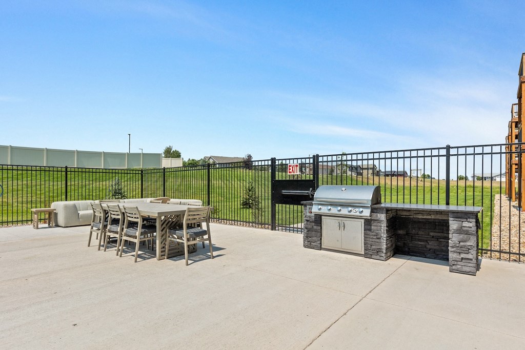 a patio with a grill and a table and chairs