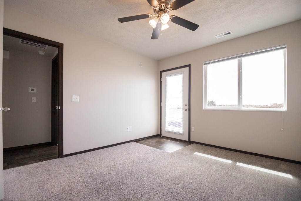 an empty living room with a ceiling fan and two windows