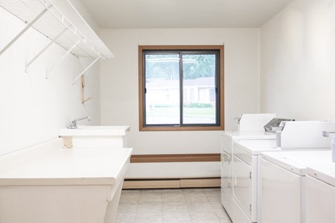 an empty kitchen with white appliances and a window
