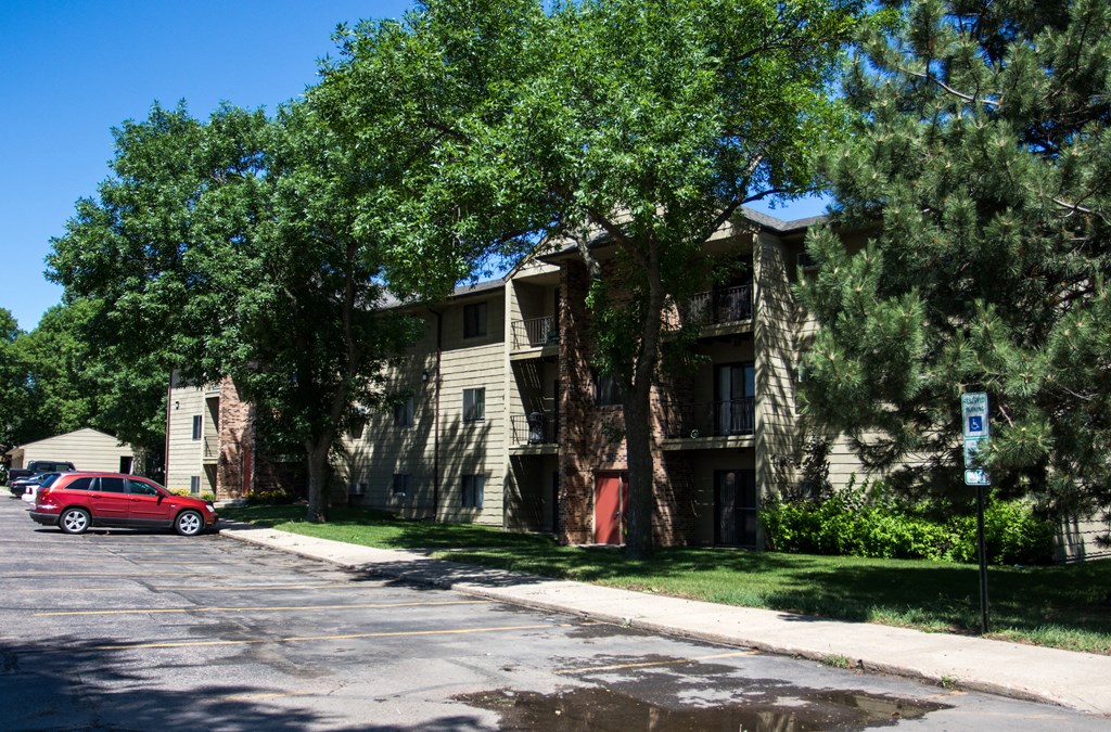 an apartment building with a red car parked in front of it
