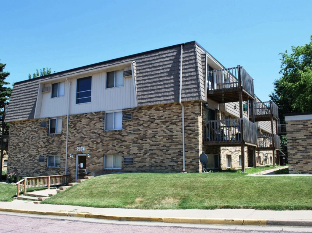 a brick apartment building with balconies and a lawn