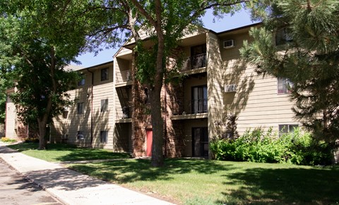 an apartment building with a lawn and trees in front of it